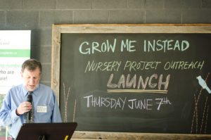 Man speaking into a microphone in front of a blackboard